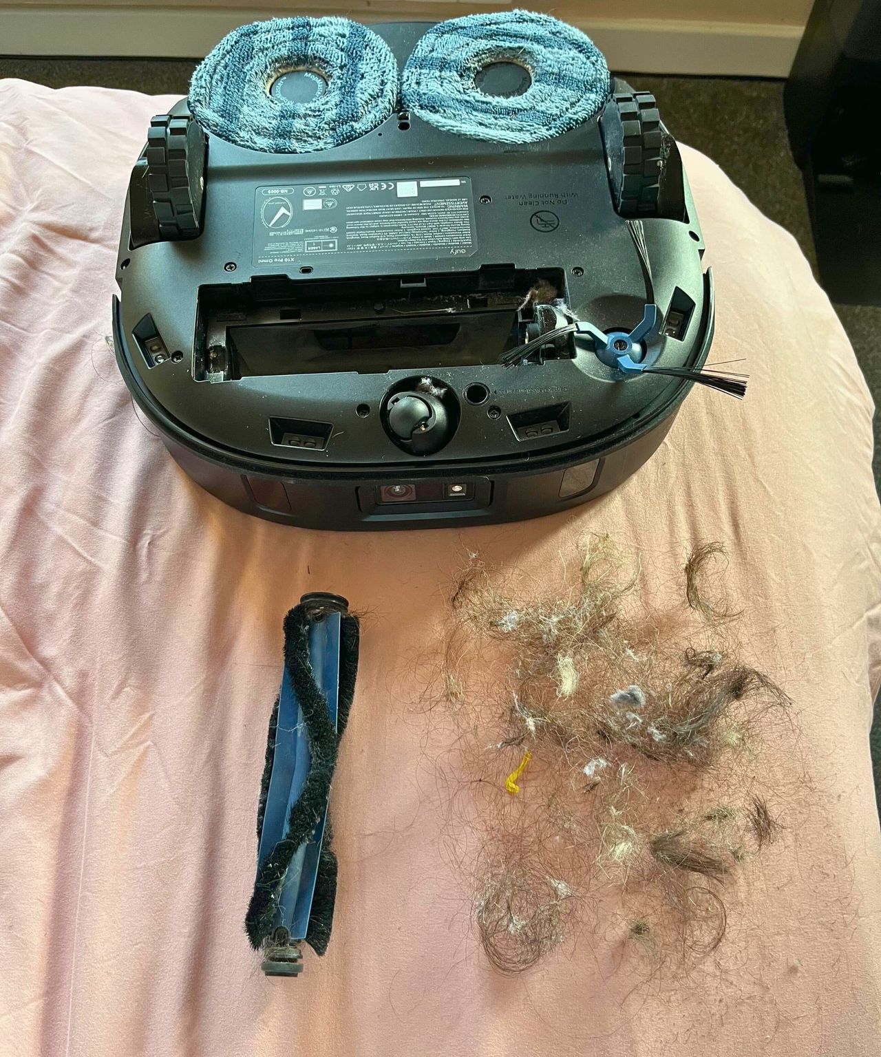 The eufy X10 Pro Omni after I cleared the hair from the brush roll with the parts separated showing three hand fulls of hair removed