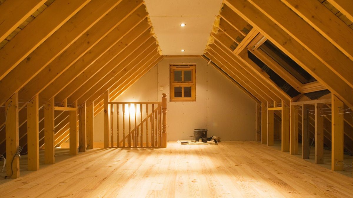 Nearly finished loft conversion with beams still exposed, and new wooden floor.