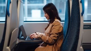 Young Asian businesswoman working on laptop while commuting by train