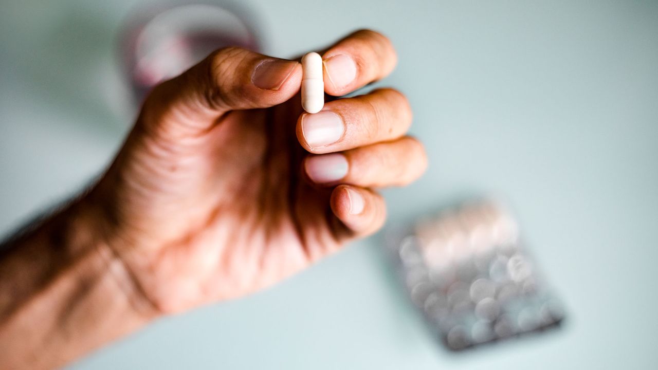 Close-up of someone&#039;s hand holding a pill.