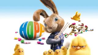 Et reklamebillede for påskefilmen Hop, hvor P.H. står med armene foldet over hinanden, iført en ternet skjorte og med to trommestikker i hånden. Rundt om ham er der en flok høns, og i baggrunden er der påskeæg og flere kaniner.