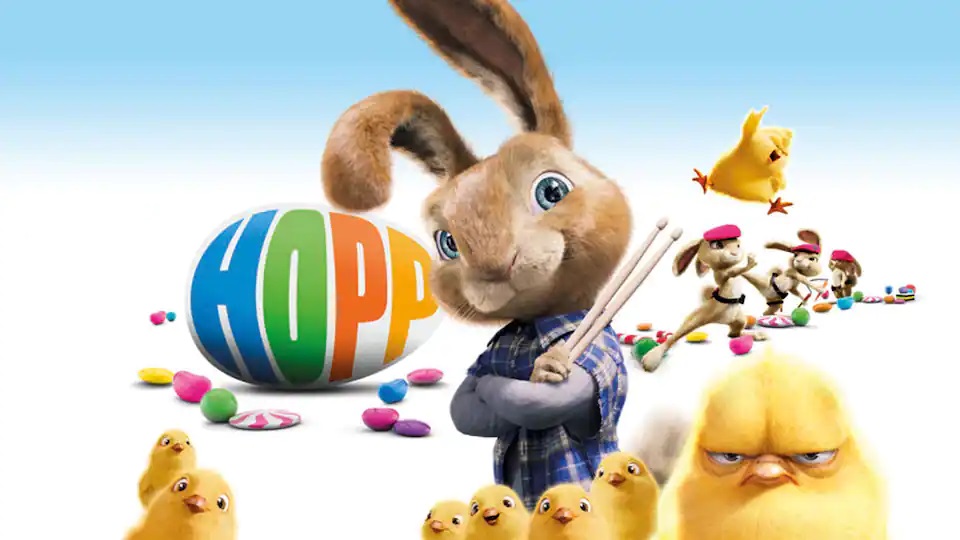 Et reklamebillede for påskefilmen Hop, hvor P.H. står med armene foldet over hinanden, iført en ternet skjorte og med to trommestikker i hånden. Rundt om ham er der en flok høns, og i baggrunden er der påskeæg og flere kaniner.