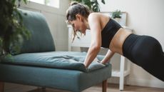 A woman doing incline push ups on the sofa