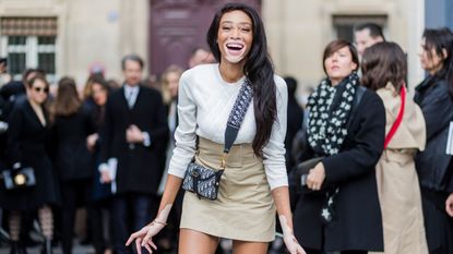 paris, france march 03 model winnie harlow wearing white knit, mini skirt, boots, dior bag outside dior on march 3, 2017 in paris, france photo by christian vieriggetty images