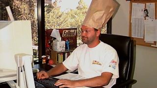 Fallout developer Tim Cain seated at computer wearing brown paper bag on head in the '90s