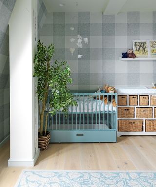 Unisex nursery ideas with gray check wallpaper, wicker basket storage and pale blue painted cot.