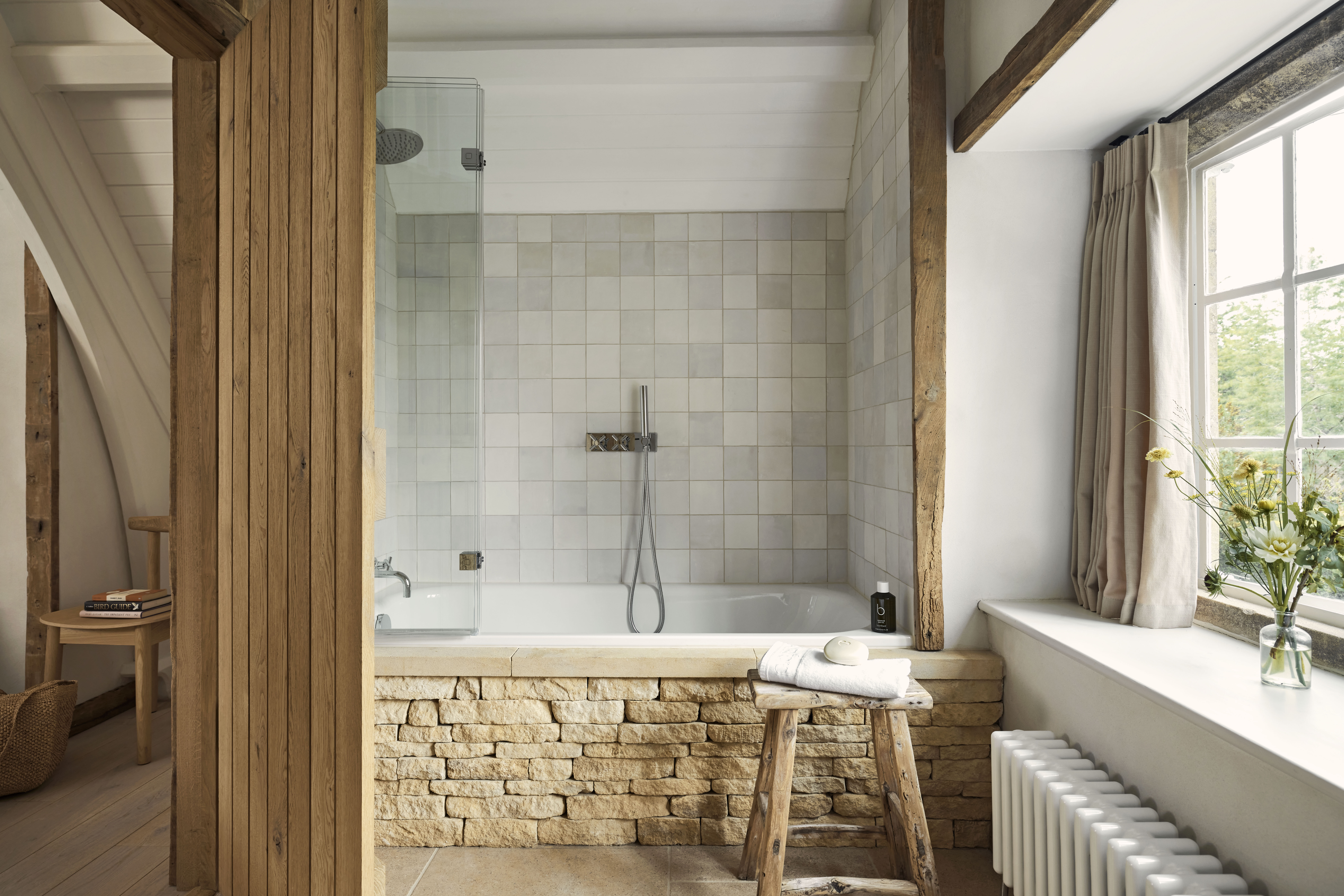 A hotel bathroom featuring a shower-bath with exposed brick surround