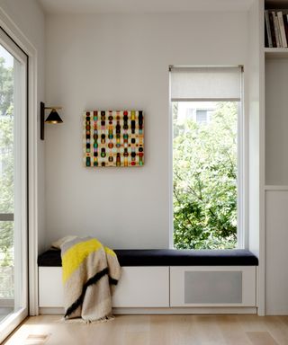 window seat in family room with white walls and yellow throw