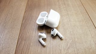 Apple AirPods 3 bredvid sitt tillhörande laddningsfodral.