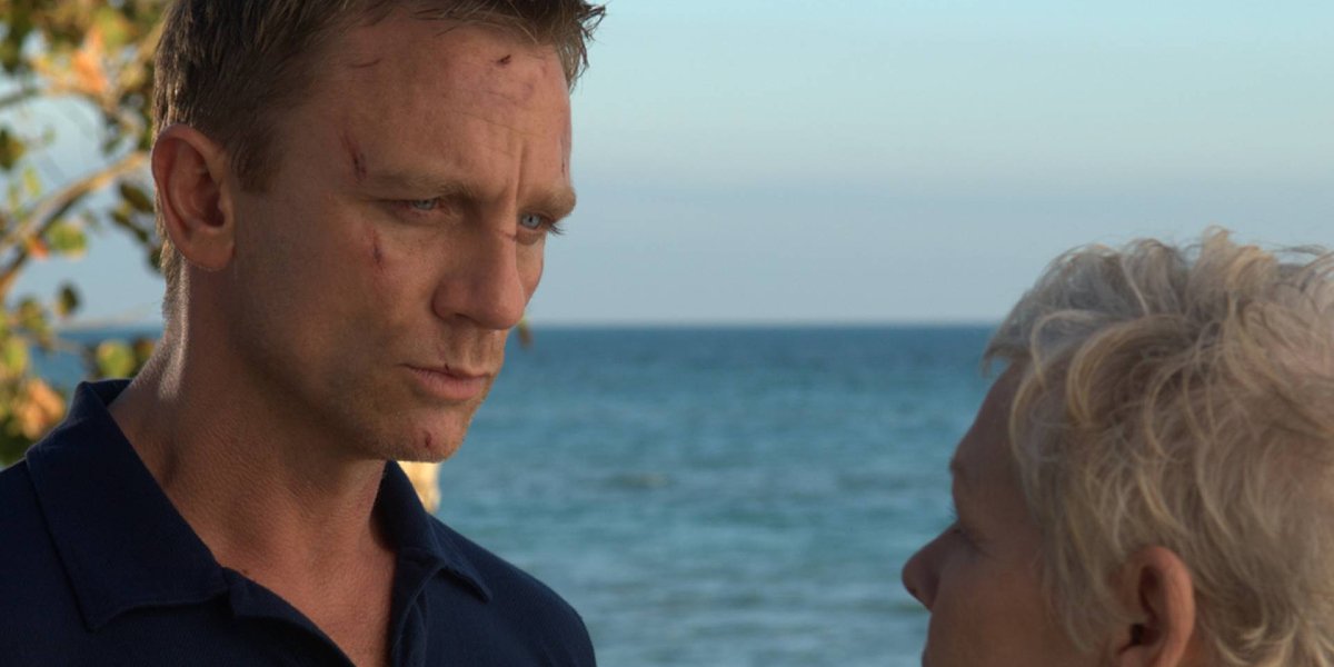 Daniel Craig stands listening to Dame Judi Dench in front of the ocean in Casino Royale.