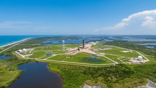 aerial image of launch pad at cape canaveral amongst green nature scenery and the coast to the left.