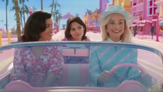 From left to right: America Ferrera riding shotgun, Ariana Greenblatt in the backseat, and Margot Robbie driving the Barbie car in Barbie Land.
