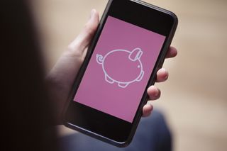 teenage boy holding cell phone with conceptual digital piggy bank on screen