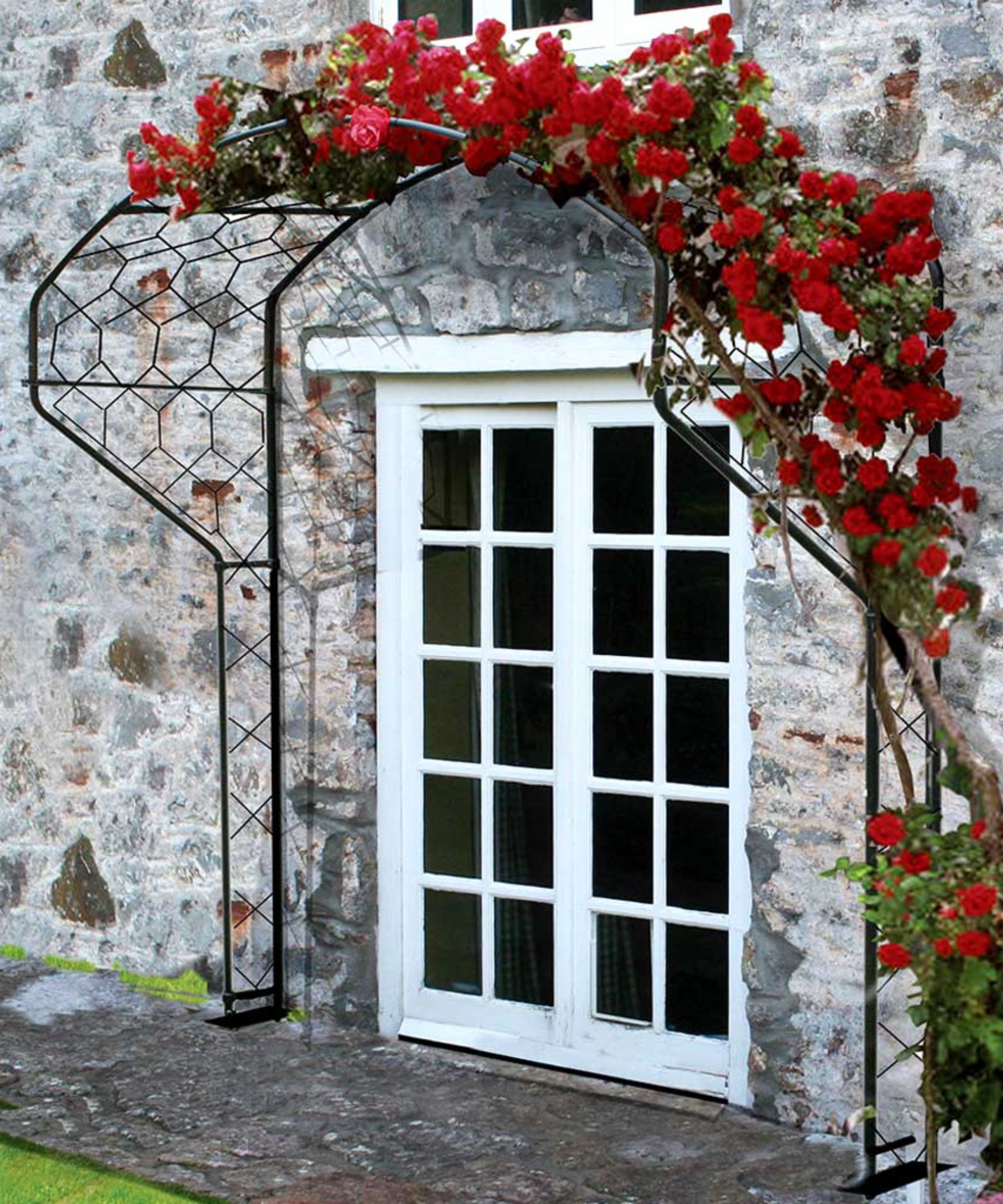iron frame covered with red flowering foliage on wall of house with rear patio door entrance