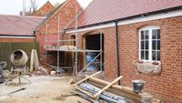 brick single storey extension in mid-construction with scaffolding and timbers in yard