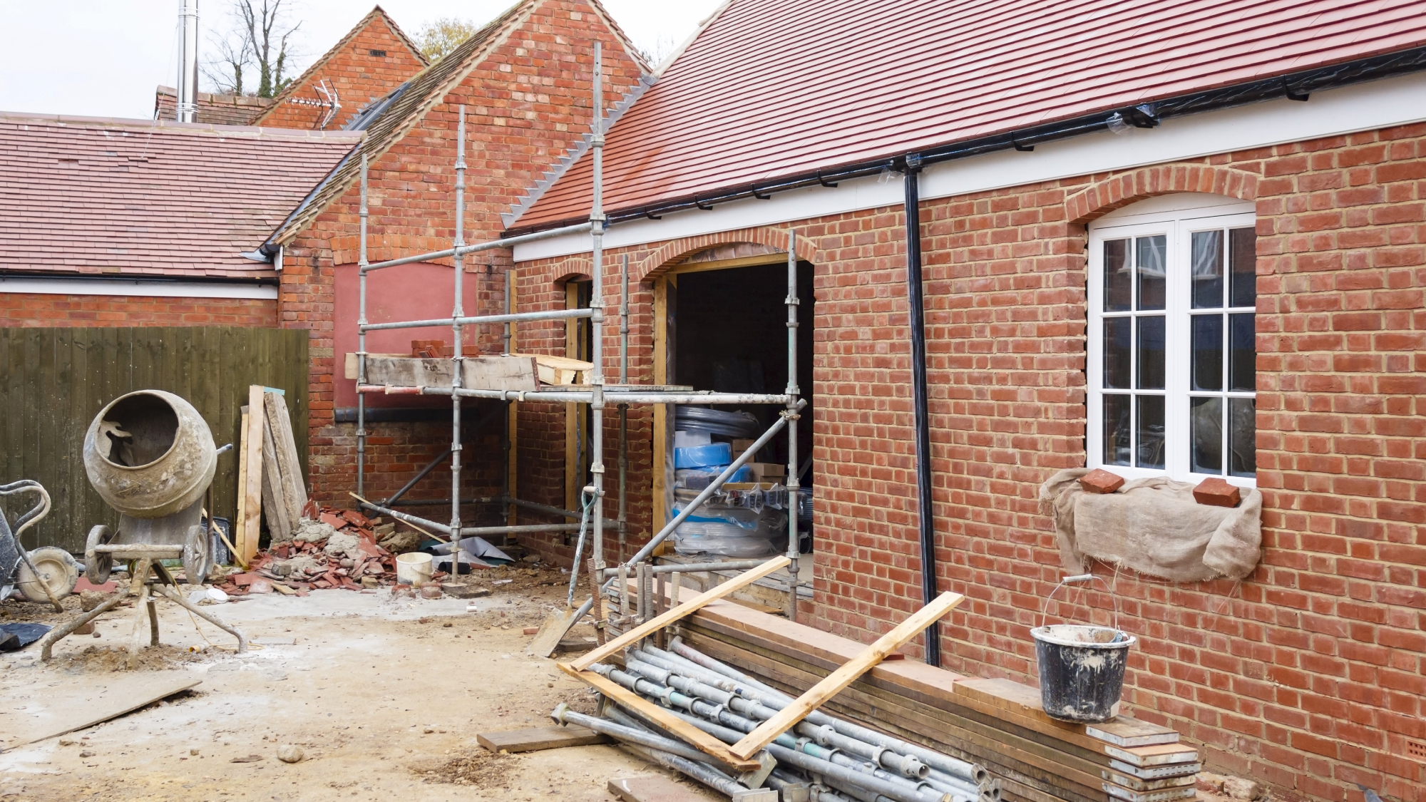 brick single storey extension in mid-construction with scaffolding and timbers in yard