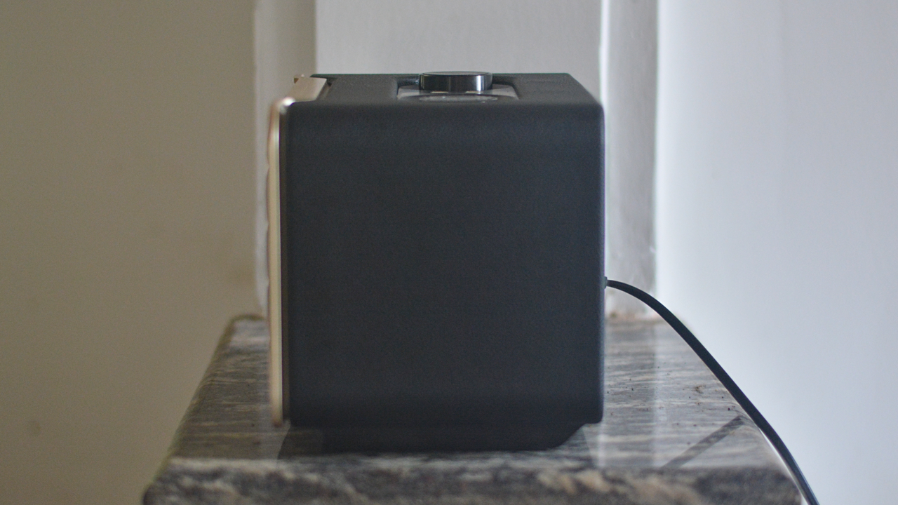 The JBL Authentics 200 speaker on a sits on a small marble surface. We can see its side of plan black plastic.