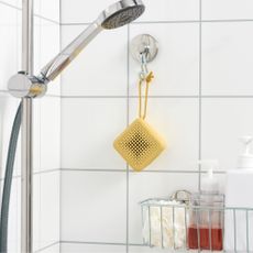 IKEA waterproof VAPPEBY speaker in yellow hanging on a hook in an all-white shower