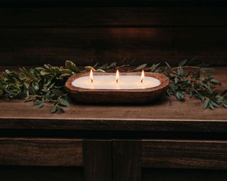 Christmas candle on wooden sideboard, christmas foliage surrounding