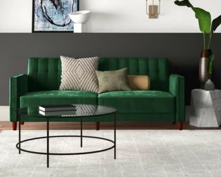 A crushed velvet green sleeper sofa in a living room with a rug and coffee table.