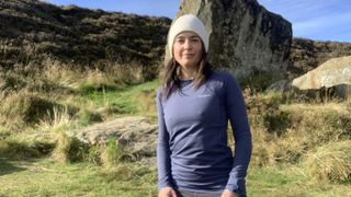 Woman hiking in blue top with large rock behind her