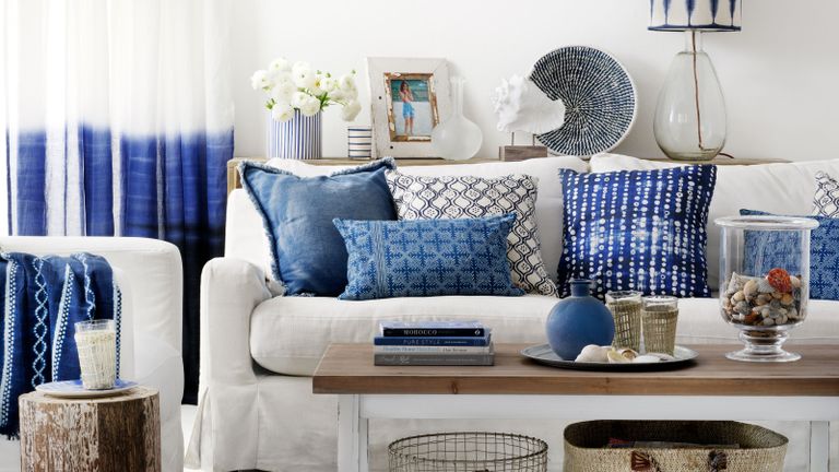 coastal living room with white walls and sofa layered with blue cushions and decor pieces