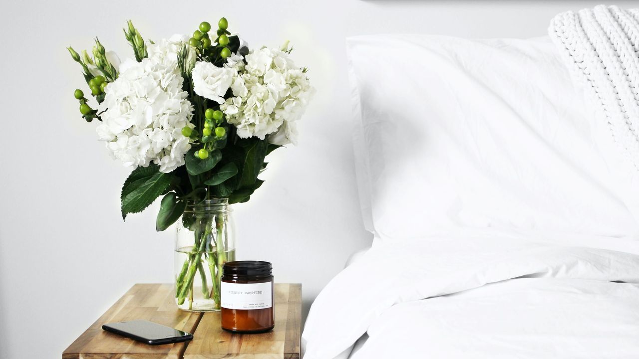 White bedroom with candle and flowers on table