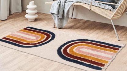Runner rug with rainbow print in hallway with white vase in shot and bench, on wooden floor