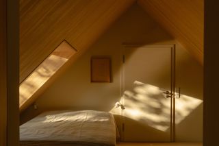 the lake house, a timber structure in a forest, made up of a cluster of volumes with pitched roofs