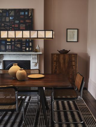 Dining room with table and chairs, and pendant light above, chest of drawers and fireplace