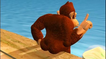 Donkey Kong sat on a boardwalk, raising a single finger with his back to the camera.