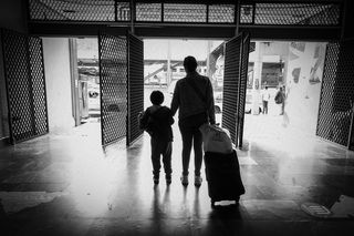 Parent and child from behind, pulling suitcase. Image from Leica Women Foto Project Awards 2023