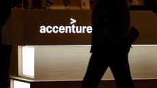 Illuminated Accenture logo pictured at CES 2026 in Las Vegas, with silhouetted man walking past in low light.