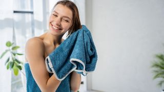 A lady drys her hair after a shower