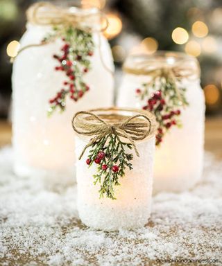 A set of glass mason jars decorated with epsom salts, twine and faux berry decor
