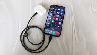 A photo of an iPhone 15 reverse charging a set of AirPods Pro
