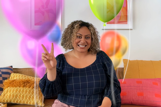 A person holding up a peace sign during a FaceTime call. Animated ballons are rising up either side of them.