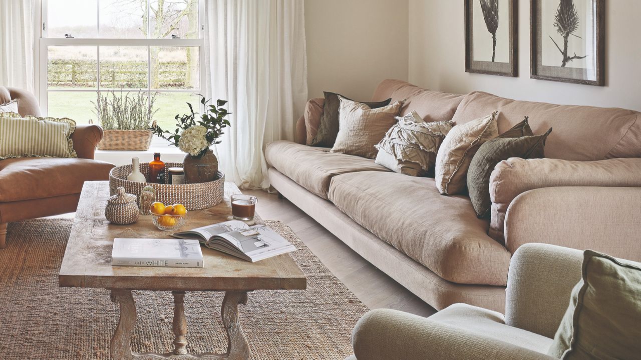 A living room with a beige sofa and earthy-coloured scatter cushions with a long rectangular wooden coffee table in front of it