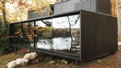 black pod with glass walls and ceiling sleek exterior in forest