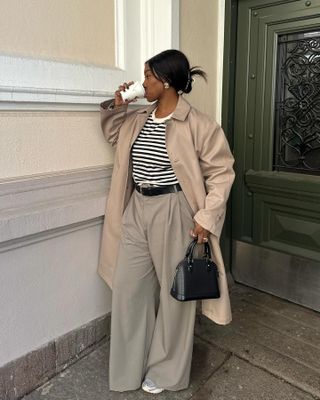 Nnenna Chem in a trench coat, striped top, and trousers.