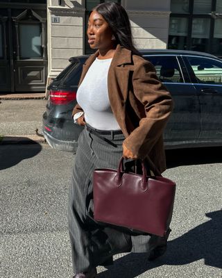 Fashion influencer Nnenna Echem wears the burgundy color trend with gray and brown suede.