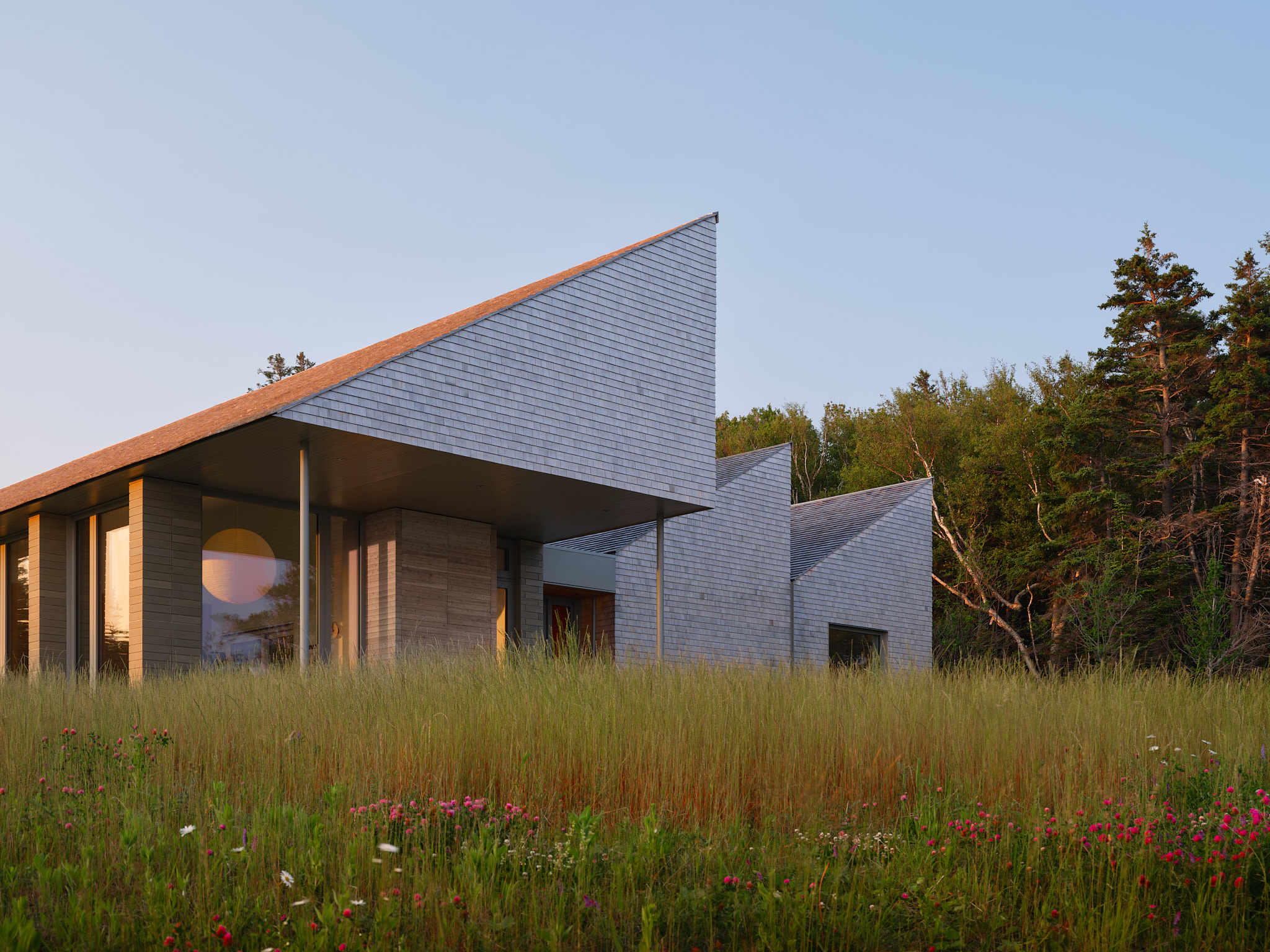 place of work's house in a meadow between the forest and the sea, an architectural, geometric house in leafy countryside