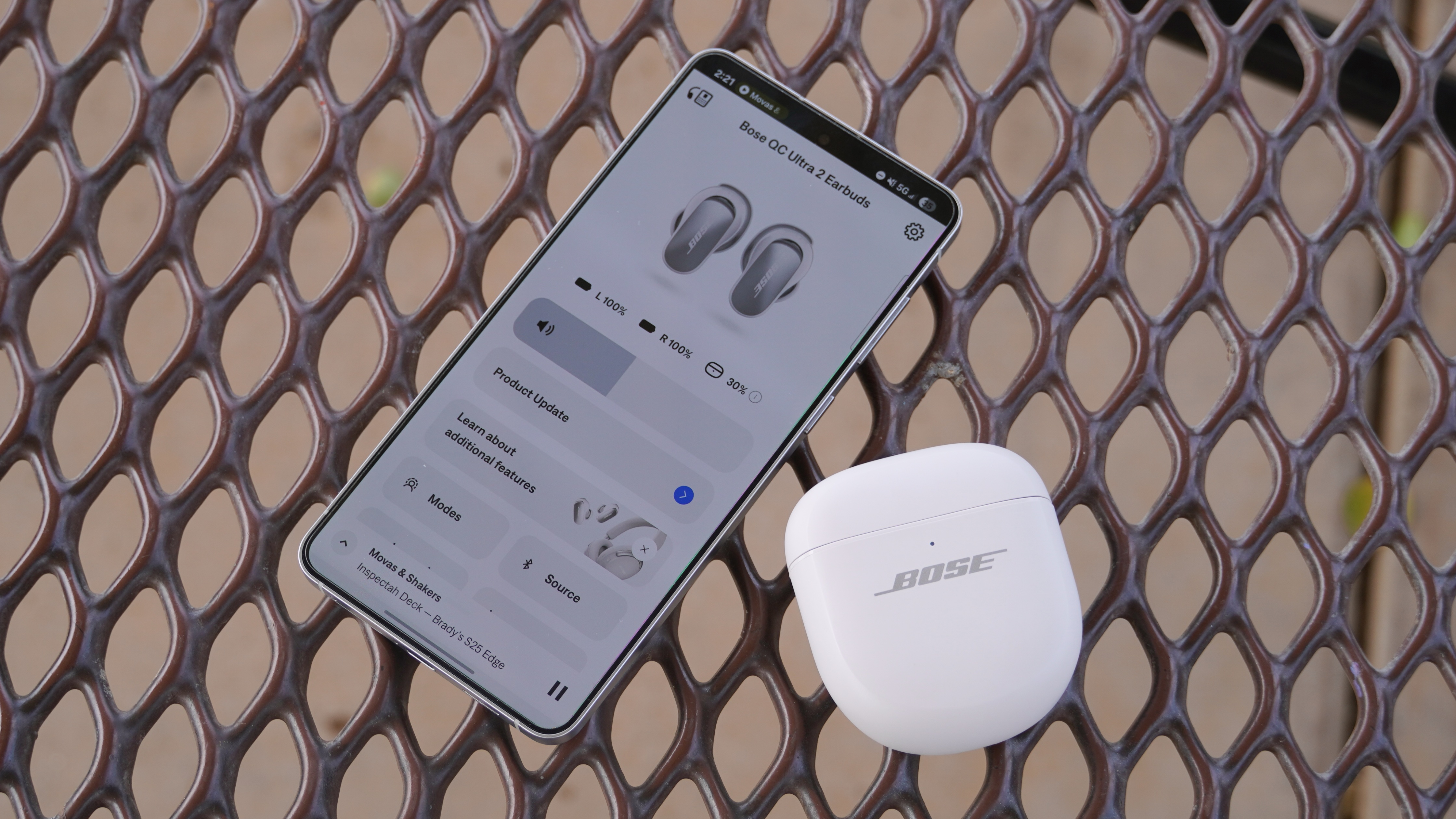 The Bose QuietComfort Ultra Gen 2 earbuds in their case beside a phone with the Bose app open.