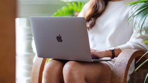 Woman working on MacBook laptop resting on knees