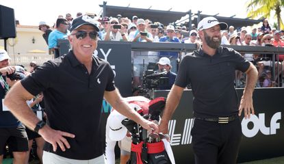 Greg Norman and Dustin Johnson stand by a golf bag