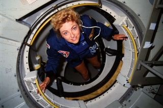 STS-40 payload specialist Millie Hughes-Fulford poses for a photo in the tunnel connecting space shuttle Columbia's middeck to the Space Life Sciences-1 (SLS-1) Spacelab module in 1991. 