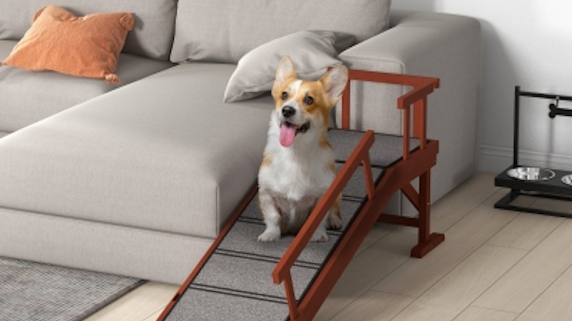 A white and tan corgi sat on a dog ramp next to a grey sofa