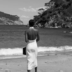 Sylvie Mus wearing a white halter midi dress on a beach in Costa Brava, Spain.