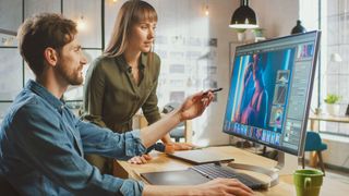 woman and man looking at monitor screen with a Photoshop image on it - best monitor for photo editing