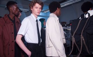 A row of people with one looking at the camera in a short sleeved shirt and tie